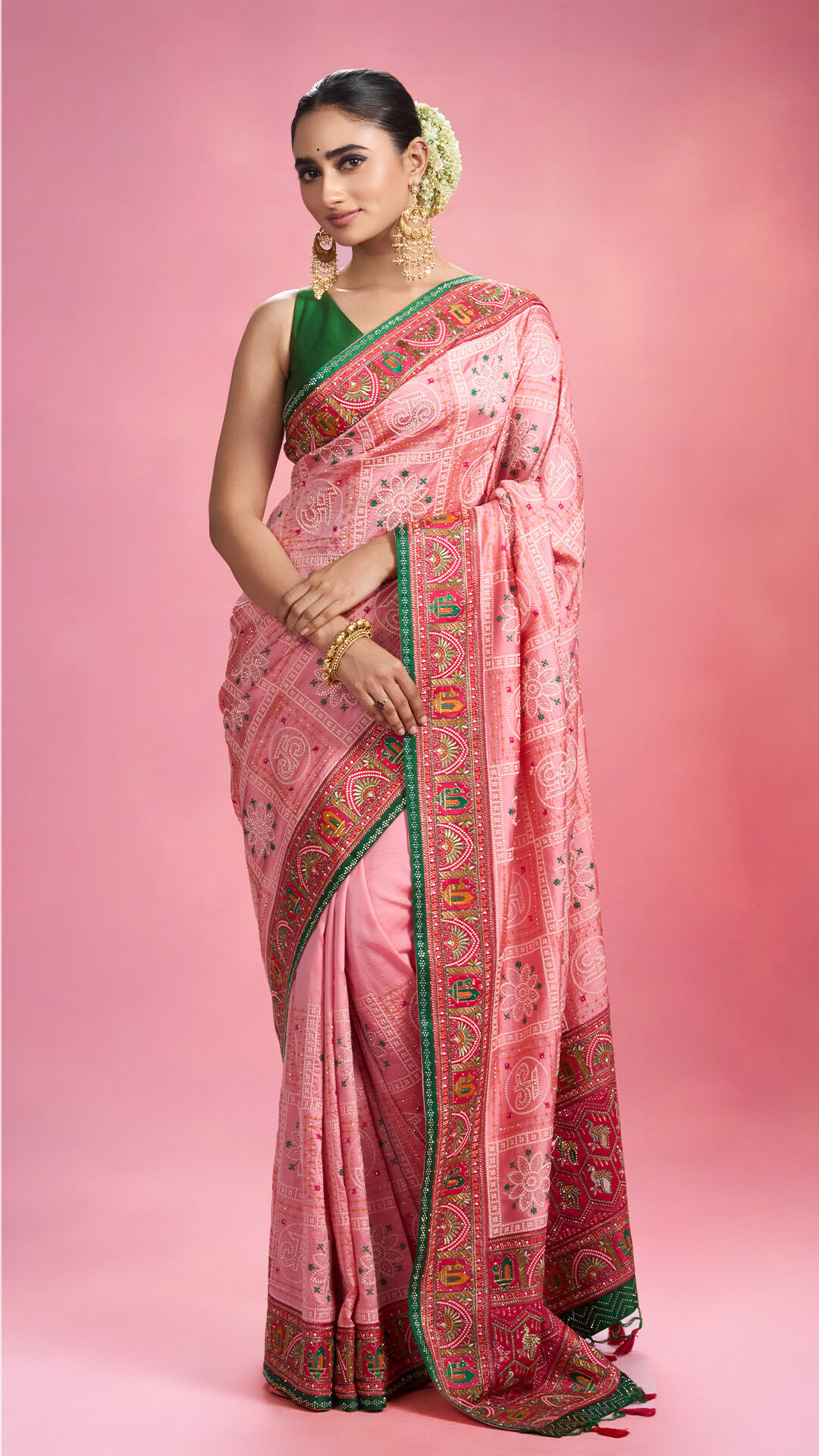 Woman wearing a traditional pink saree with green border, ideal for showcasing saree care tips